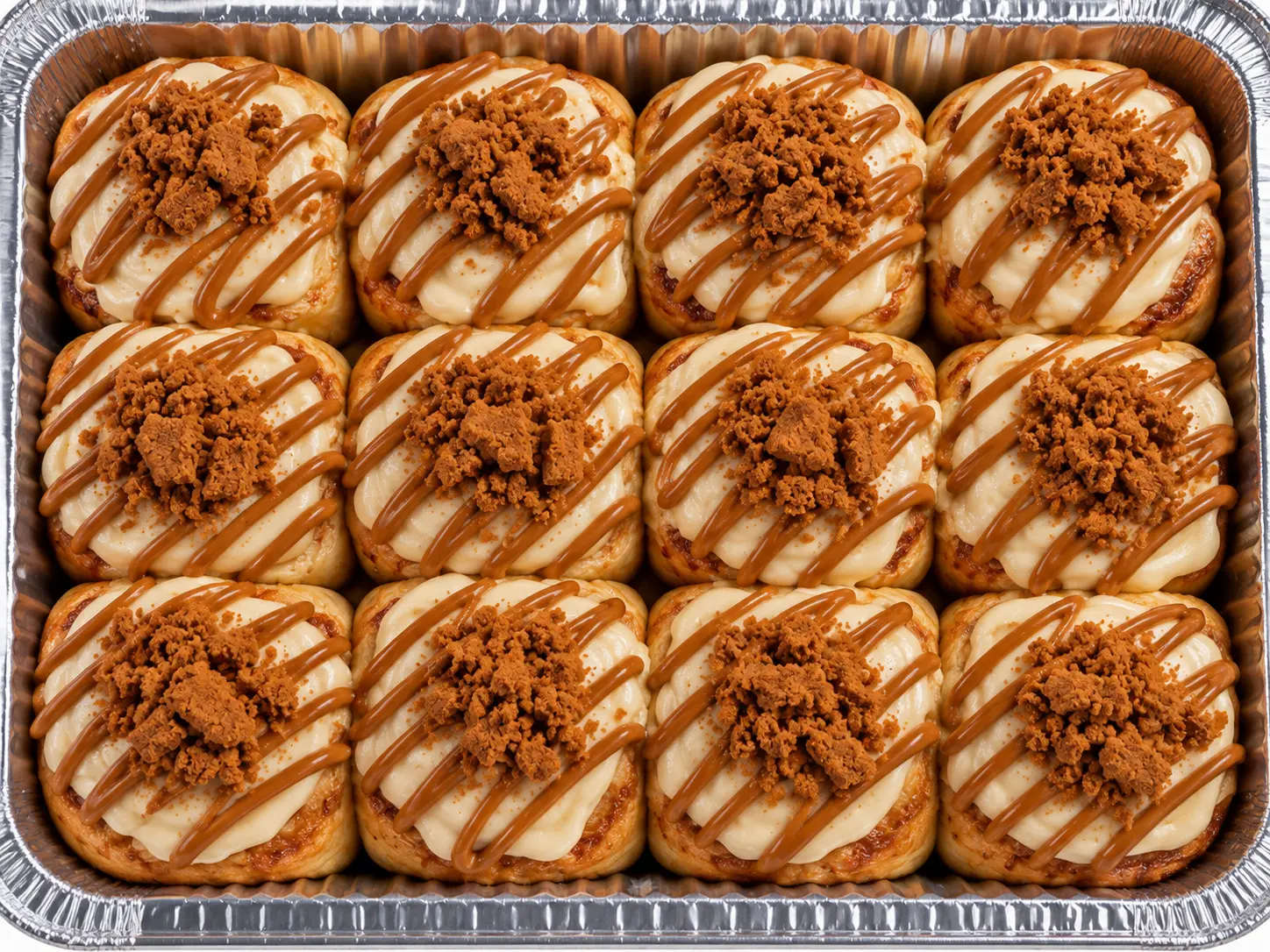 A pan of biscoff cinnamon rolls with cookie butter drizzle and cookie crumble