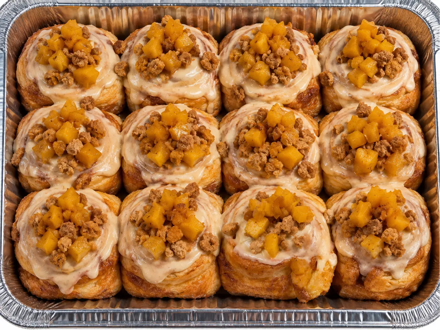 A pan of peach cobbler cinnamon rolls topped with spiced peaches and crumble