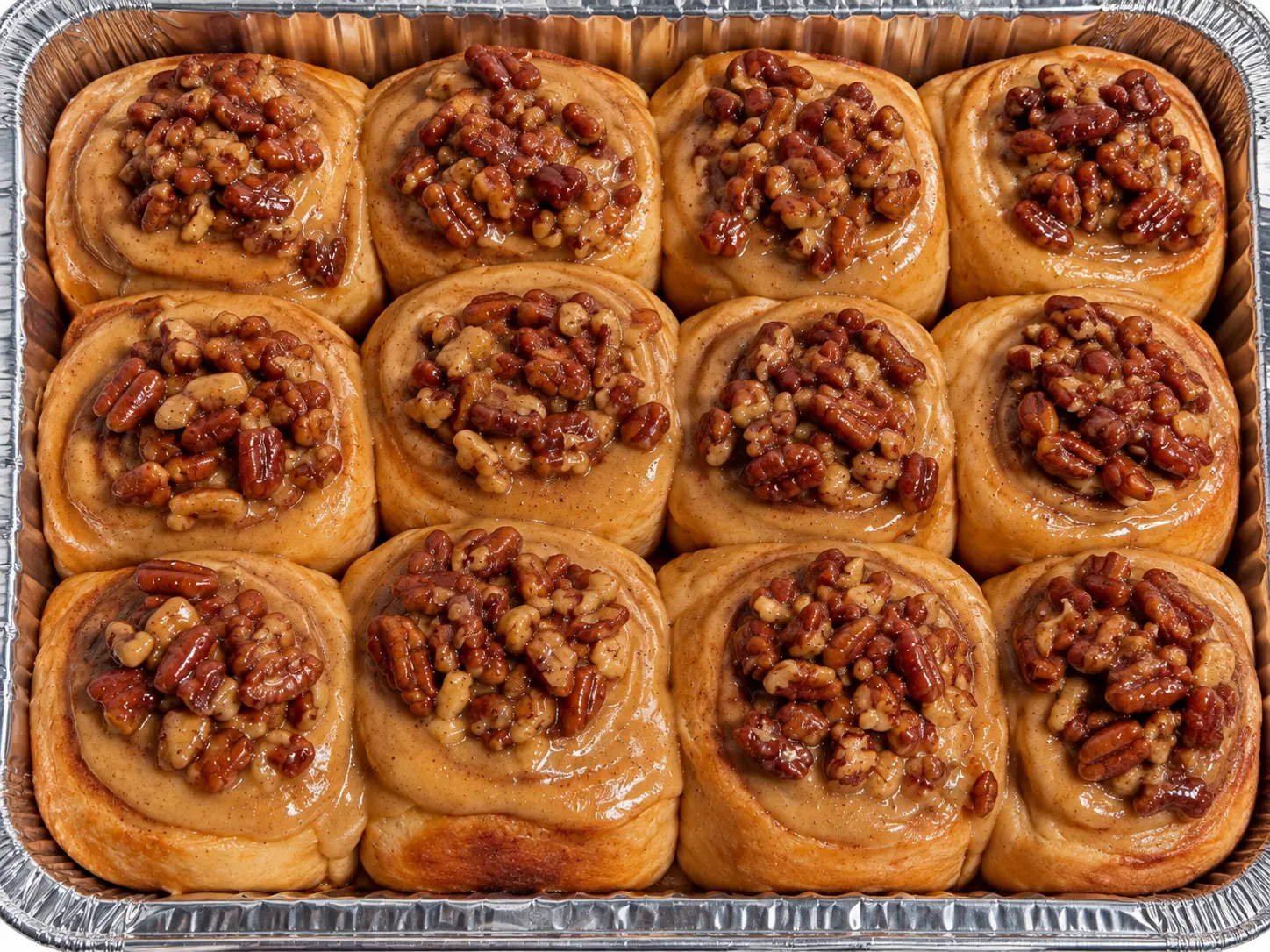 A pan of maple pecan cinnamon rolls topped with glazed pecans